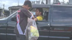 Menino vendendo biscoito de polvilho para motorista parado no trânsito