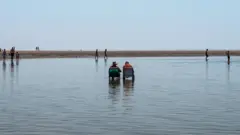 Duas cadeiras de praia no meio da água