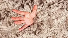 mão de pessoa 'sufocando em areia movediça'