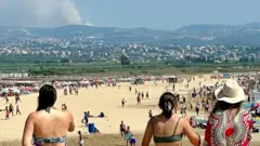 Pessoas com roupa de banho assistindo a explosões 