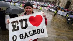 Manifestante segura cartaz com a frase 'Eu amo o galego' durante ato na cidade de Santiago de Compostela, na Galícia, em defesa da promoção e da preservação da língua galega