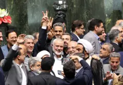 No centro da imagem, Ismail Haniyeh faz sinal de vitória cercado por legisladores iranianos no parlamento iraniano em Teerã