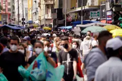 Pessoas com máscaras andando em rua 