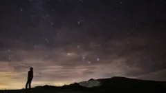 Ilustração de homem observando chuva de meteoros