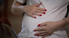 A woman puts her hands on her pregnant stomach
