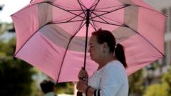 A woman in Mexico shelters herself from heat with an umbrella