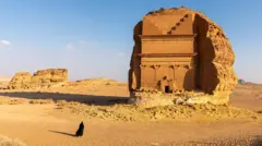 Mulher com traje típico caminha no deserto, perto de templo