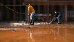 Duas pessoas fazem limpeza de calçada 