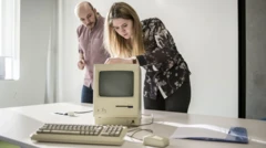 Duas pessoas perto de computador Macintosh antigo