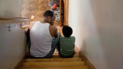 Pai e filho sentados na escada 