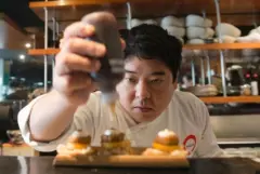 Homem amarelo com roupa de chef montando um prato