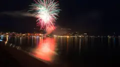 Mar visto com fogos de artifício ao fundo 