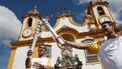 Atletas carregam a tocha olímpica em frente a uma igreja no Brasil em 2016