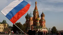 Jovem agita bandeira russa na frente da praça Vermelha, em Moscou