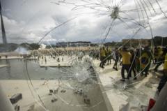 Vidraça do Palácio do Planalto quebrada e manifestantes ao fundo