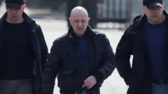 Yevgeny Prigozhin caminhando ao lado de dois homens