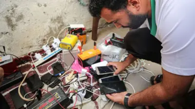 homem recarregando seu telefone em uma estação na faixa de Gaza