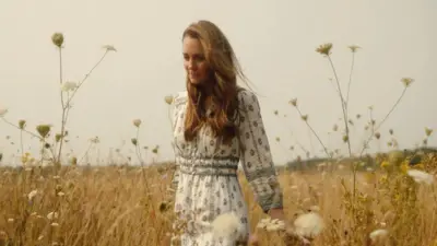 A foto mostra a princesa Kate Middleton caminhando em um campo.