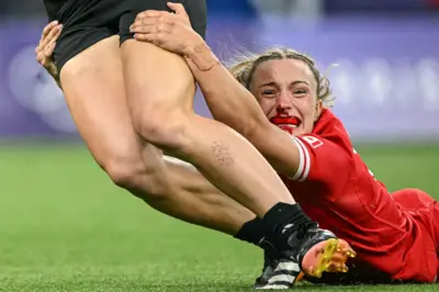 Jogadora canadense ensangrentada tenta capturar uma rival no rugby