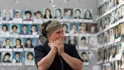 Mulher chorando ao ver as fotos das vítimas do ataque no ginásio da escola de Beslan.