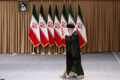 Aiatolá Ali Khamenei caminha em frente à bandeiras do Irã; ele veste túnica preta