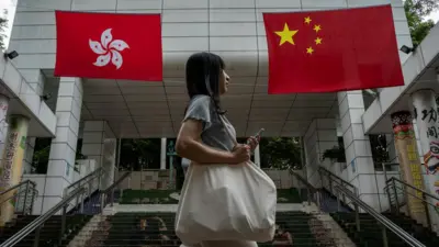 一名女子走过香港特区和中国国旗前