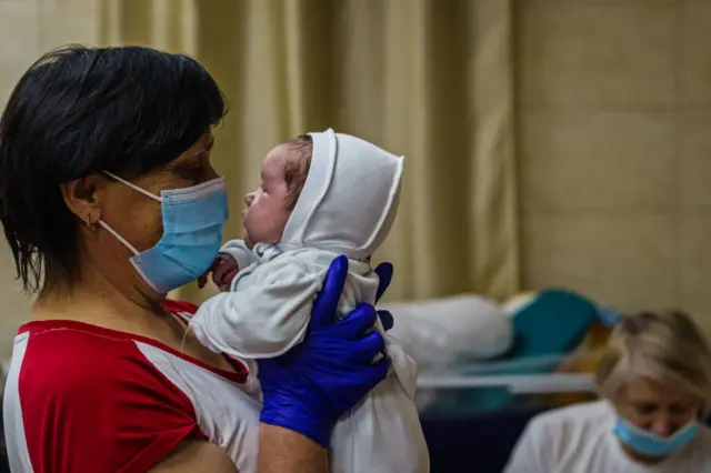 Uma enfermeira com um bebê no berçário subterrâneo de Kiev