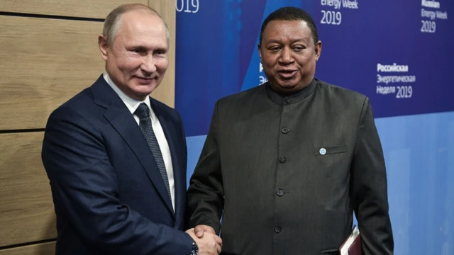O presidente da Rússia, Putin, e o secretário-geral da Opep, Mohammad Barkindo, apertam as mãos.