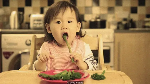 Menina comendo aspargos
