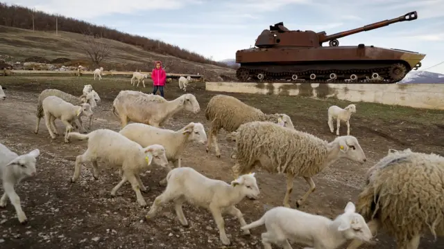 Una niña kosovar cerca de un tanque serbio destruido en la guerra.