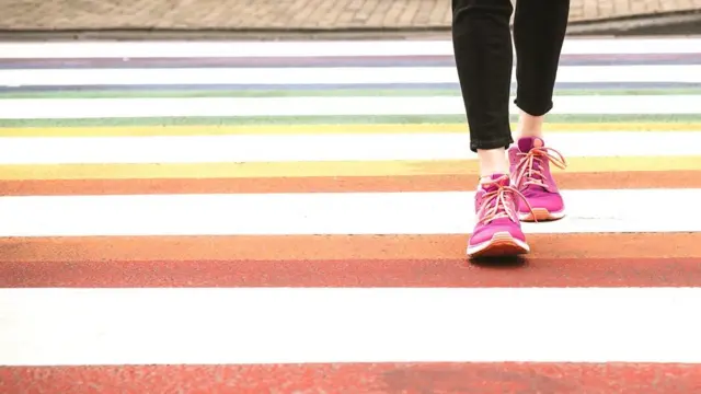 Foto mostra detalhe de pés atravessando a rua