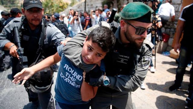 Un policía israelí detiene a un adolescente palestino