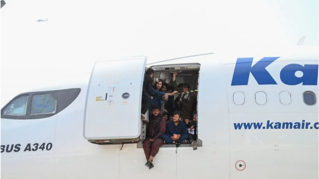 Povo afegão sobe em um avião e se senta à porta enquanto espera no aeroporto de Cabul