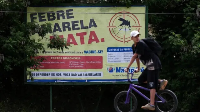 Homem passa em frente a placa que diz 'Febre amarela mata'