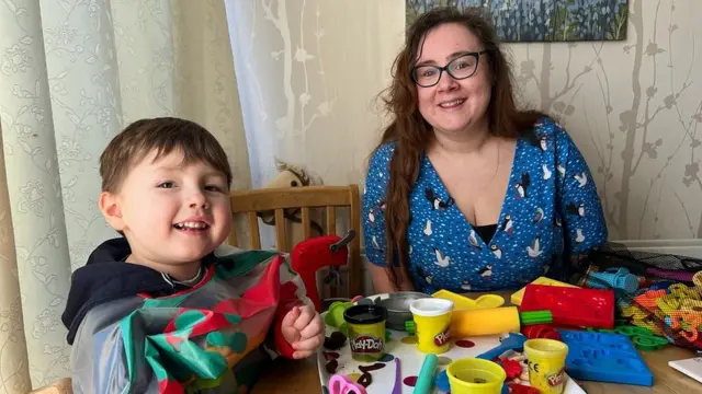 Teddy sentado com a mãe Beth brincando de massinha