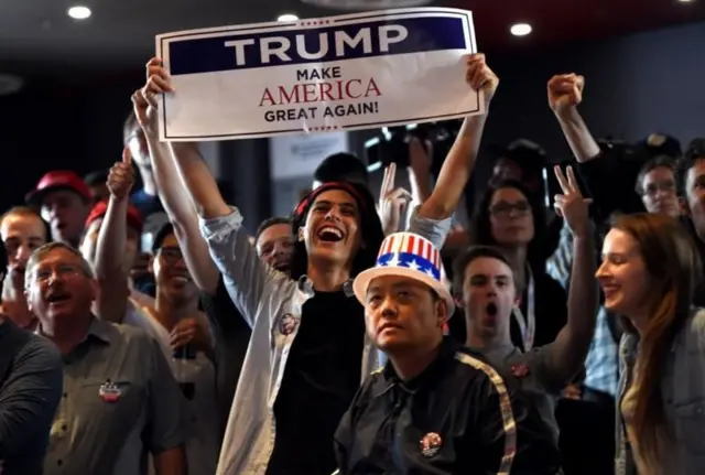 Apoiadores de Trump segurando cartaz com slogan  'Make America Great Again' 