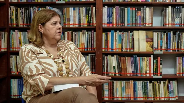 Rosana Gaspar sentando em frente a biblioteca