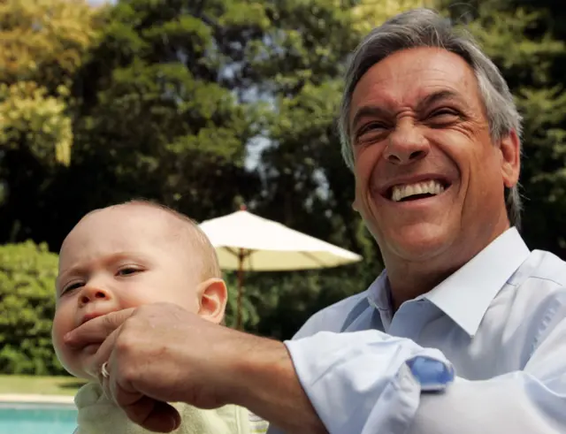 Sebastián Piñera sorrindo e com o dedo na boca do neto 