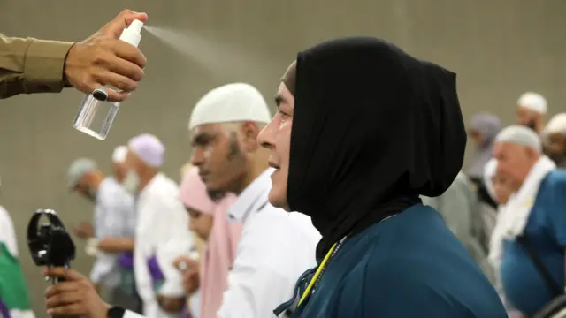 Um oficial borrifa água no rosto de uma mulher 