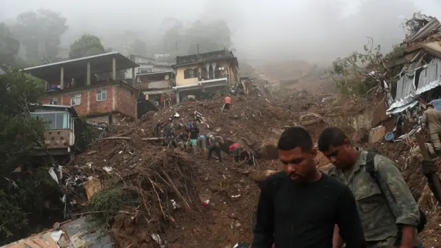 Pessoas procuram por sobreviventes em área destruída por deslizamento