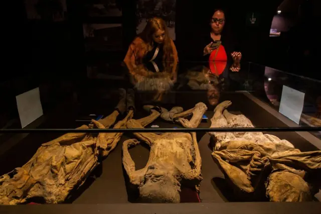 Visitantes observam três múmias no Museu das Múmias de Guanajuato