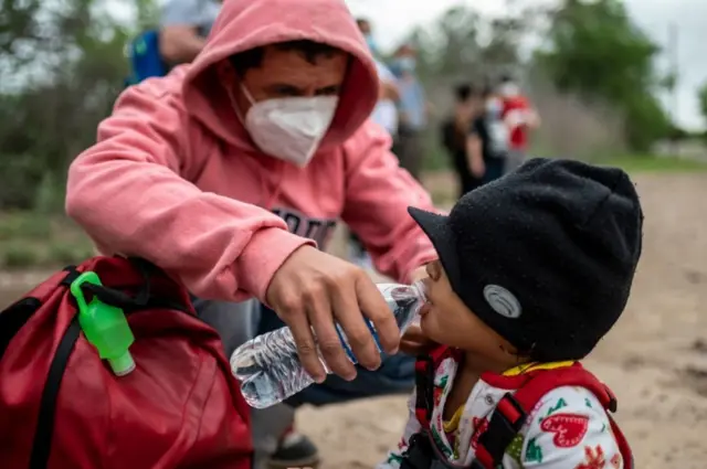 Um migrante dá água à sua filha de 2 anos perto da fronteira EUA-México em Del Rio, Texas. Foto tirada em 16 de maio de 2021