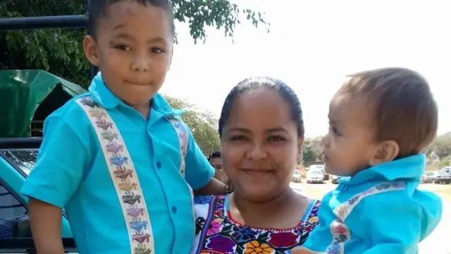 Kenia Hernández com seus filhos no colo, sorrindo, antes de ser detida.