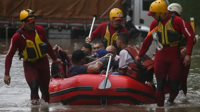 Bombeiros usam bote para resgatar pessoas ilhadas em enchente