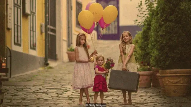 Três meninas segurando flores e balões