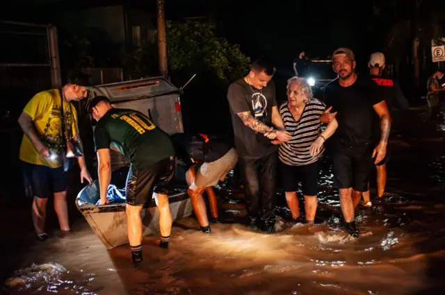 Voluntários ajudam idosa em meio à enchente