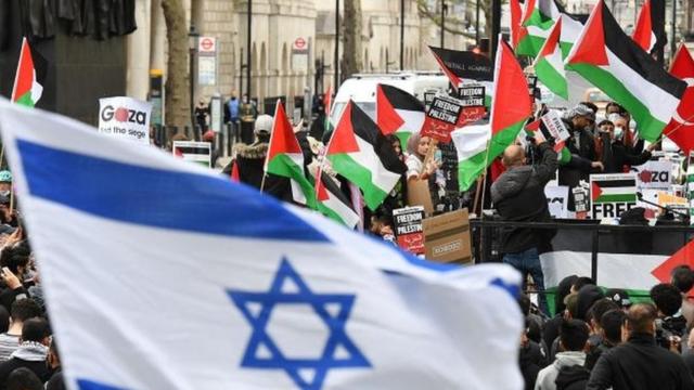 Una bandera israelí con banderas palestinas en el fondo, durante una manifestación en Londres, 11 mayo 2021
