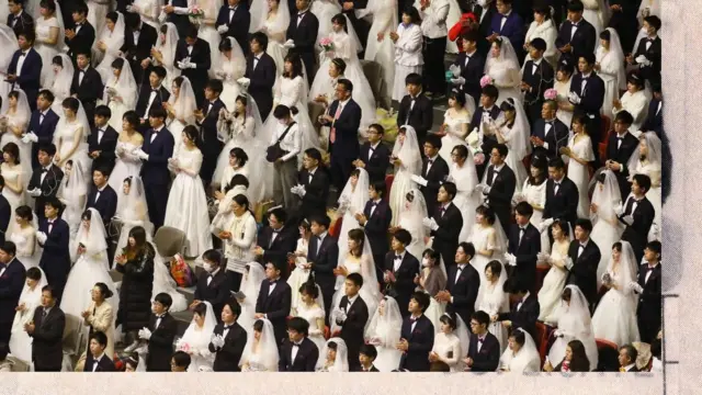 Foto de cima mostra dezenas de casais amarelos - noivos de terno e noivas de branco - que olham para a mesma direção 