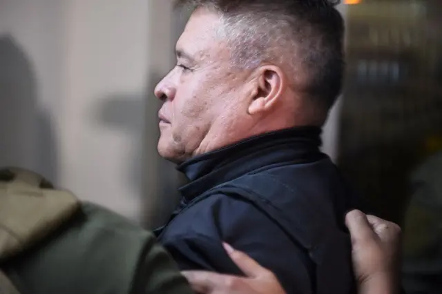 Zúñiga de perfil, escoltado por policiais