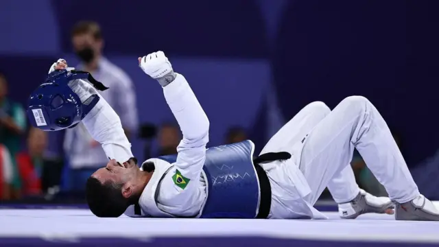 Netinho deitado no chão enquanto comemora a conquista do bronze